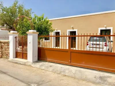 a fence in front of a building with a car at Bekos traditional house in Archangelos