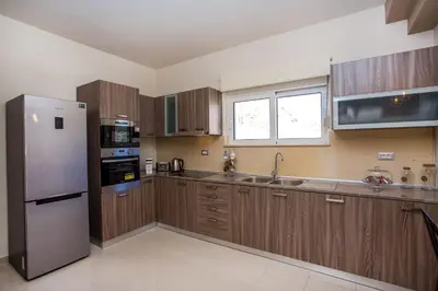 a kitchen with wooden cabinets and a stainless steel refrigerator at MeFoMi Villa in Rhodes Town
