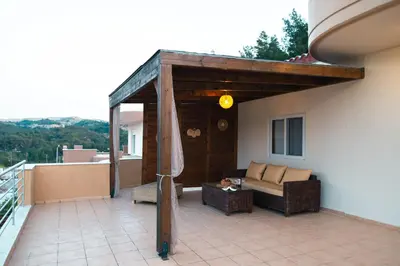 a patio with a couch and a table on a balcony at MeFoMi Villa in Rhodes Town