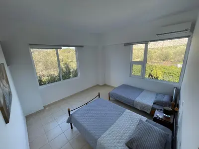 a bedroom with two beds and two windows at Villa Epavlis Haraki in Haraki