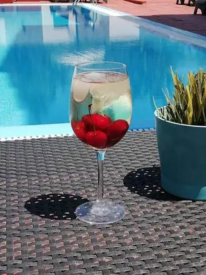 a glass of wine sitting on a table next to a pool at Platoni Elite Villas in Ialyssos