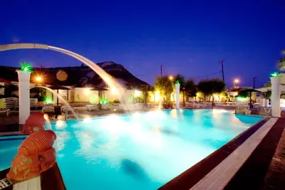 a large swimming pool at night with a fountain at Billy's Studios in Faliraki