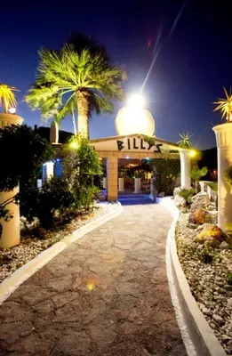 a building with a sign that reads kill with palm trees at Billy's Studios in Faliraki
