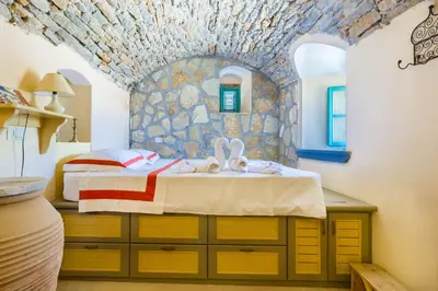 a bedroom with a bed and a stone wall at Villa Ricolas in Symi