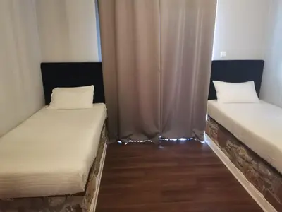 two beds in a room with curtains and wooden floors at Ataviros Hotel in Émbonas