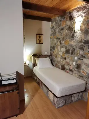 a bed in a room with a stone wall at Ataviros Hotel in Émbonas