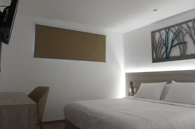 a bedroom with a white bed and a wooden desk at Vallian Village Hotel in Paradeísion