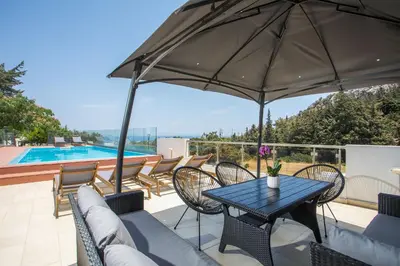a patio with a table and chairs and an umbrella at Villa Melia in Koskinou