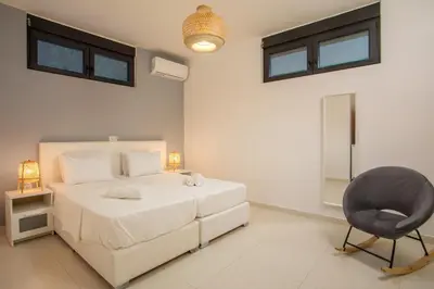 a bedroom with a white bed and a chair at Villa Melia in Koskinou