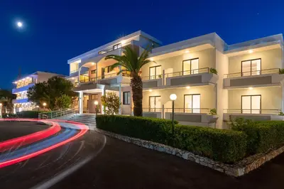 a white building with a palm tree in front of it at Meliton Hotel in Theologos
