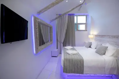 a white bedroom with a bed and a tv at Rhodos Horizon Blu-Adults Only in Rhodes Town