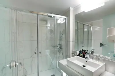 a white bathroom with a shower and a sink at Rhodos Horizon Blu-Adults Only in Rhodes Town