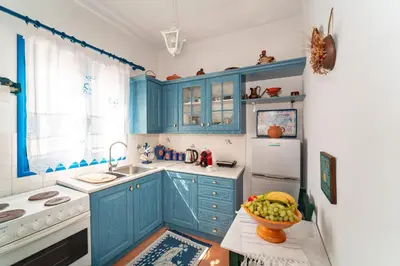 a kitchen with blue cabinets and a bowl of fruit on a table at Irene's house in Lachania