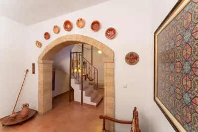 a hallway with a staircase and an arch with plates on the wall at Irene's house in Lachania