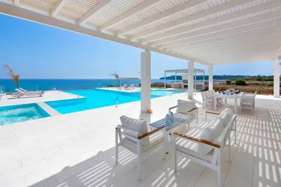 a patio with a table and chairs and a pool at Maria & Nada Beachfront Villas in Kolimbia