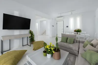 a living room with a couch and a tv on a wall at Maria & Nada Beachfront Villas in Kolimbia