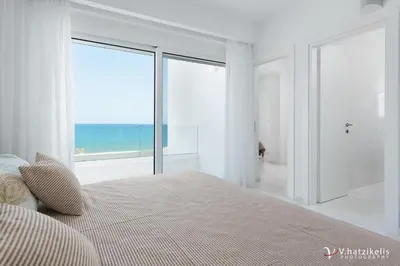 a bedroom with a bed with a view of the ocean at Maria & Nada Beachfront Villas in Kolimbia
