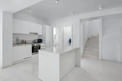 a white kitchen with white cabinets and a staircase at Maria & Nada Beachfront Villas in Kolimbia