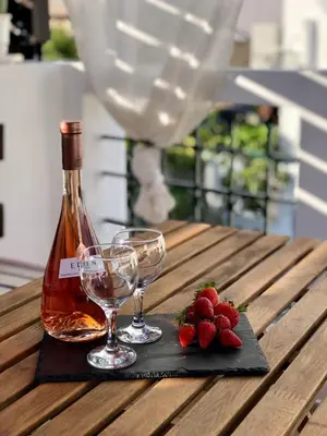 a bottle of wine and two glasses on a wooden table at Villa Smaragdi-Despoina in Malona Village