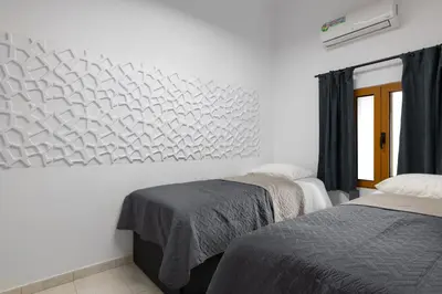 a bedroom with two beds and a white wall at A Unique 3-4 bedrooms house in OLD TOWN in Rhodes Town