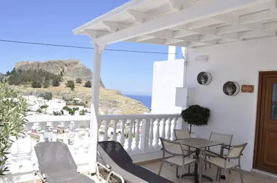 a balcony with a table and chairs and a view of the ocean at Bakia Lindos in Líndos