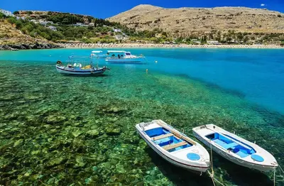 two boats are docked in the clear blue water at Bakia Lindos in Líndos