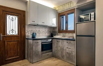 a kitchen with white cabinets and a stainless steel refrigerator at Bakia Lindos in Líndos