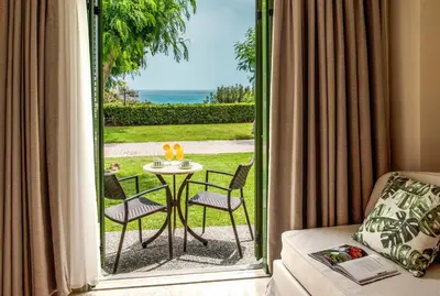 a room with a door open to a patio with a table and chairs at Mitsis Rodos Maris in Kiotari