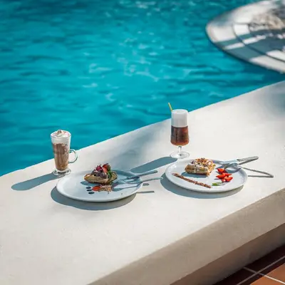 two plates of food on a table next to a pool at Mitsis Rodos Maris in Kiotari