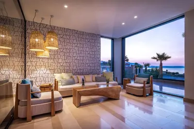 a living room with furniture and a large window at Mitsis Rodos Village in Kiotari
