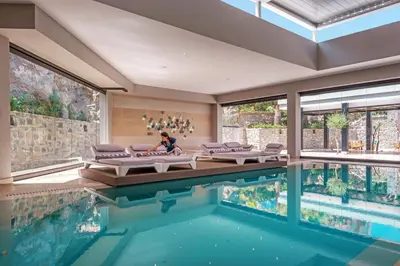 a house with a swimming pool with a woman sitting next to the pool at Mitsis Rodos Village in Kiotari