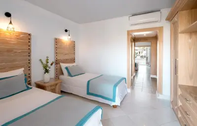 a hotel room with two beds and a hallway at Mitsis Rodos Village in Kiotari