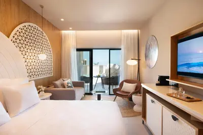 a bedroom with a living room with a large television at Mitsis Rodos Village in Kiotari