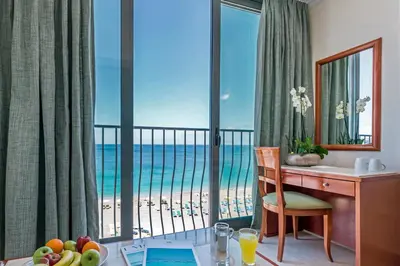 a room with a desk and a view of the beach at Mitsis La Vita in Rhodes Town