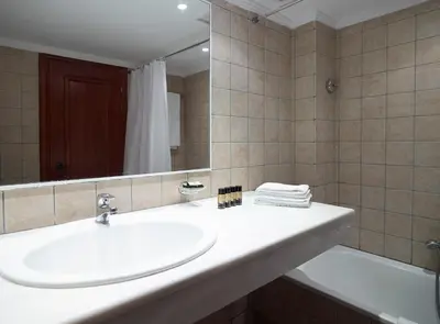 a bathroom with a sink and a mirror and a tub at Mitsis La Vita in Rhodes Town