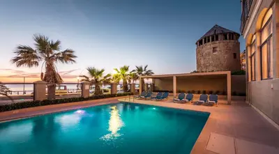 a swimming pool in front of a building with a tower at Mitsis La Vita in Rhodes Town