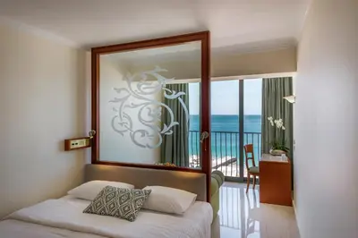 a bedroom with a bed with a mirror and a balcony at Mitsis La Vita in Rhodes Town