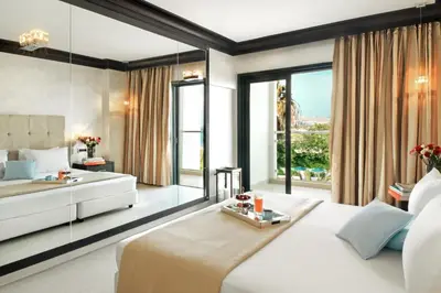 a bedroom with a white bed and a large window at Mitsis Faliraki in Faliraki