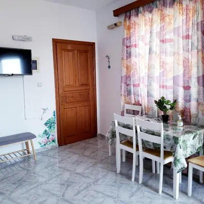 a dining room with a table and chairs and a television at Haraki Sunrise Apartments in Haraki