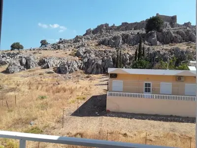 a building in front of a rocky mountain at Haraki Sunrise Apartments in Haraki