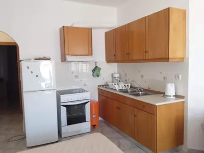 a kitchen with a white refrigerator and wooden cabinets at Haraki Sunrise Apartments in Haraki