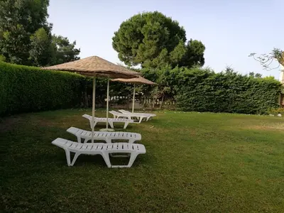 four white benches sitting in a field with an umbrella at Golden days in Afantou