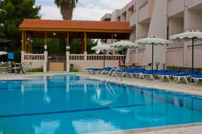 a swimming pool at a hotel with chairs and umbrellas at Golden days in Afantou