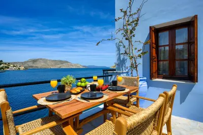 a table and chairs on a balcony with a view of the ocean at Marias Sea House in Symi