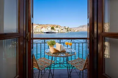 a balcony with a table and chairs with a view of the water at Marias Sea House in Symi