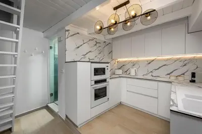 a kitchen with white cabinets and marble counter tops at Marias Sea House in Symi
