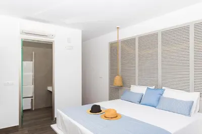 a bedroom with a bed with two hats on it at Lindos Del Mar Suites - Adults Only in Líndos