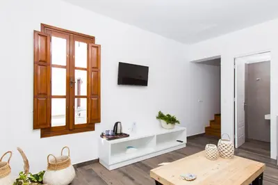 a living room with a table and a tv on a wall at Lindos Del Mar Suites - Adults Only in Líndos