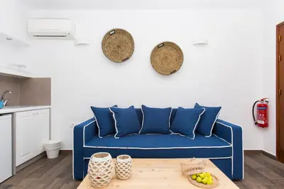 a blue couch in a living room with a table at Lindos Del Mar Suites - Adults Only in Líndos