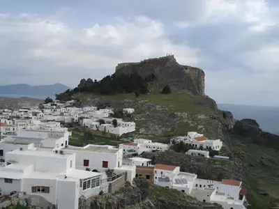 a group of white buildings on a hill with the ocean at Lindos Del Mar Suites - Adults Only in Líndos